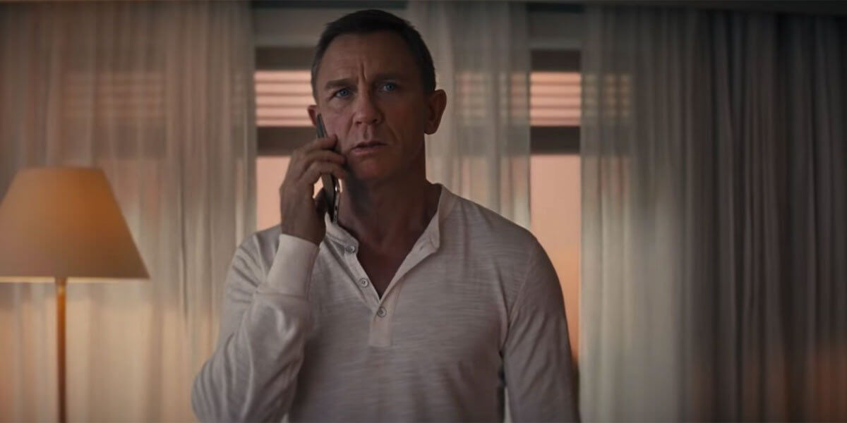 Daniel Craig menggunakan pakaian warna putih dan sedang melakukan panggilan telepon